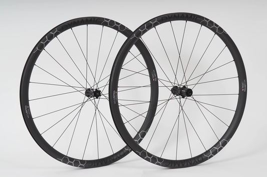 Two bicycle wheels with black rims and white spokes on a light gray background